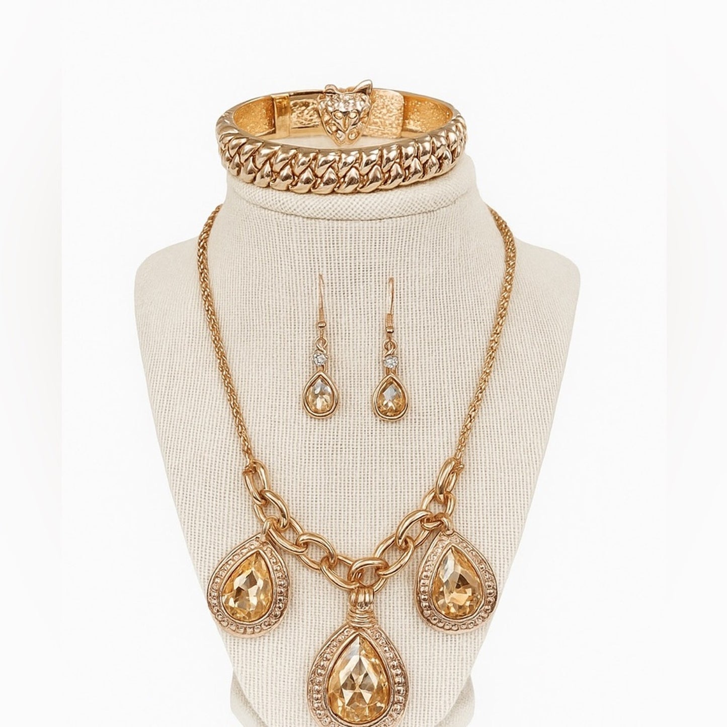 Gold jewelry set including necklace, earrings, and bracelet on a mannequin bust.