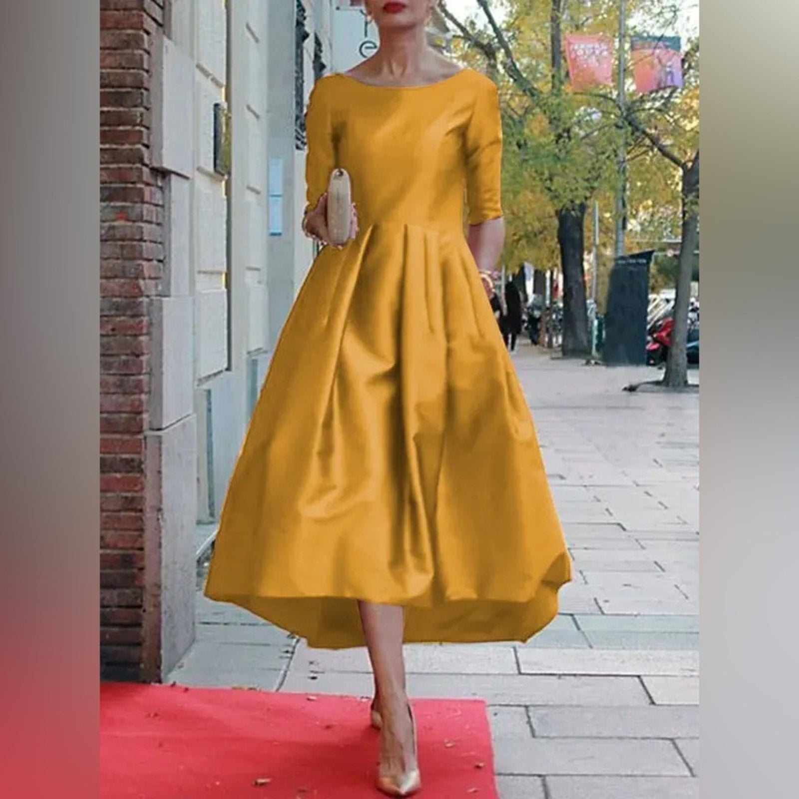 Woman in a yellow dress standing on a red carpet with a city street background