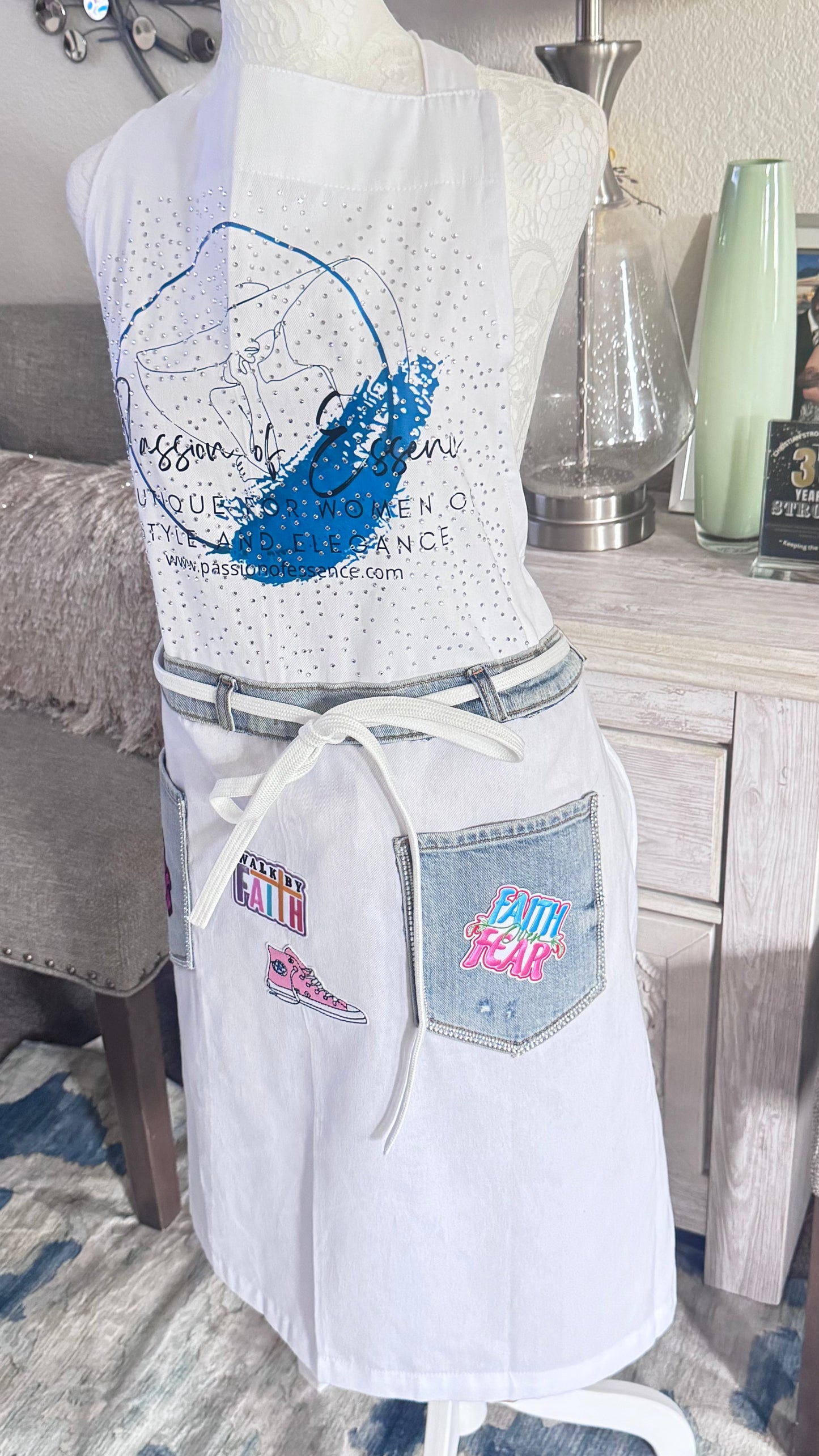 White apron with blue graphic design on a mannequin against a neutral background
