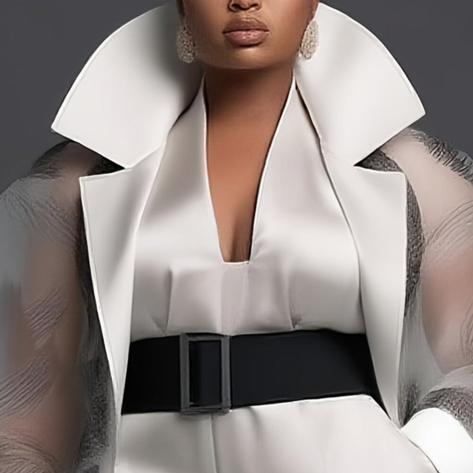 Person wearing a white outfit with a black belt against a dark background