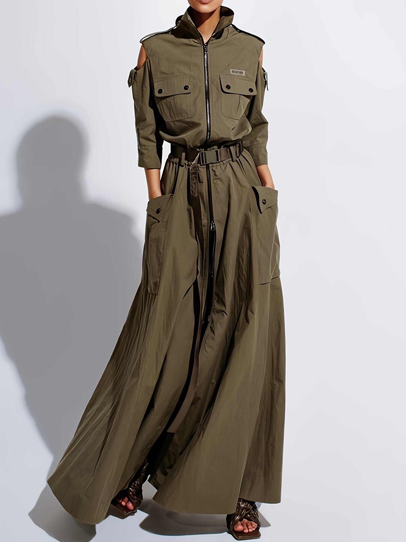 Person wearing a long olive green jumpsuit on a white background