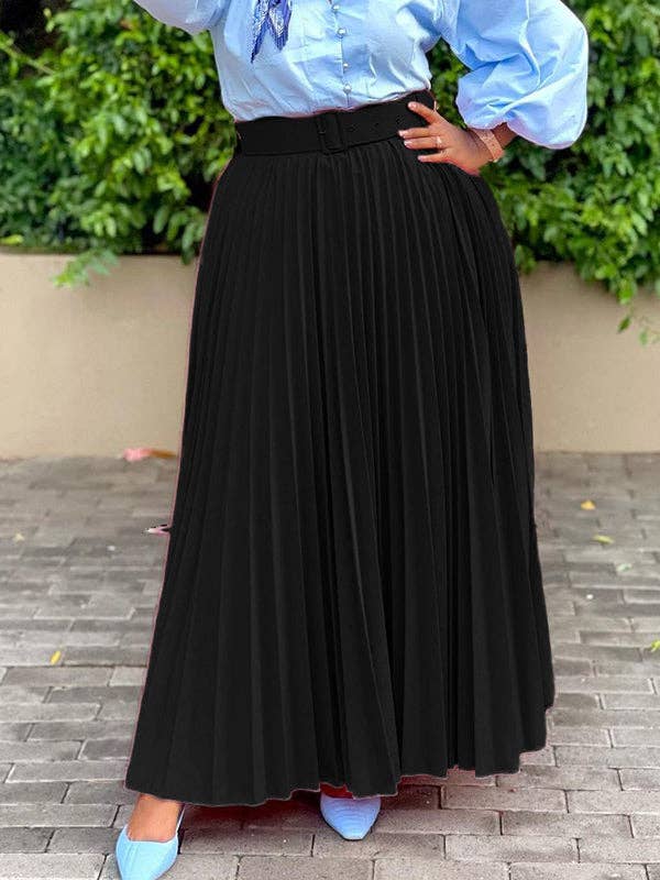 Person wearing a black pleated skirt with a light blue blouse against a green foliage background.