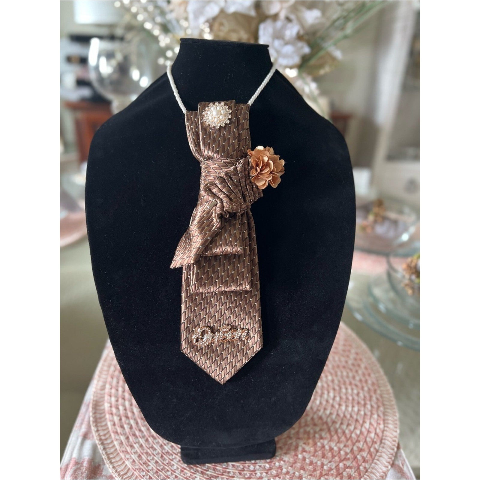 Brown textured tie with decorative elements on a black stand