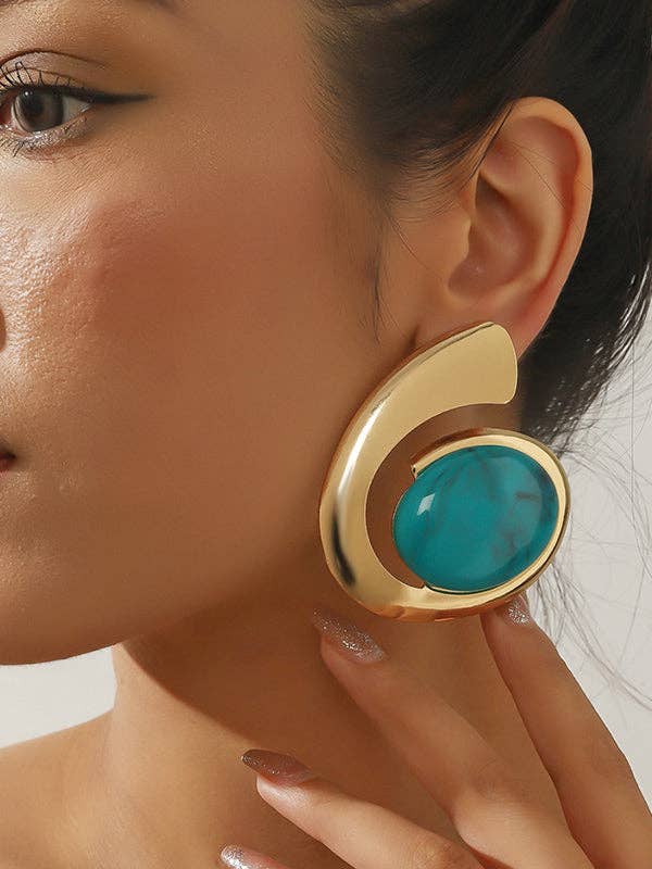 Gold earring with a turquoise stone worn by a model