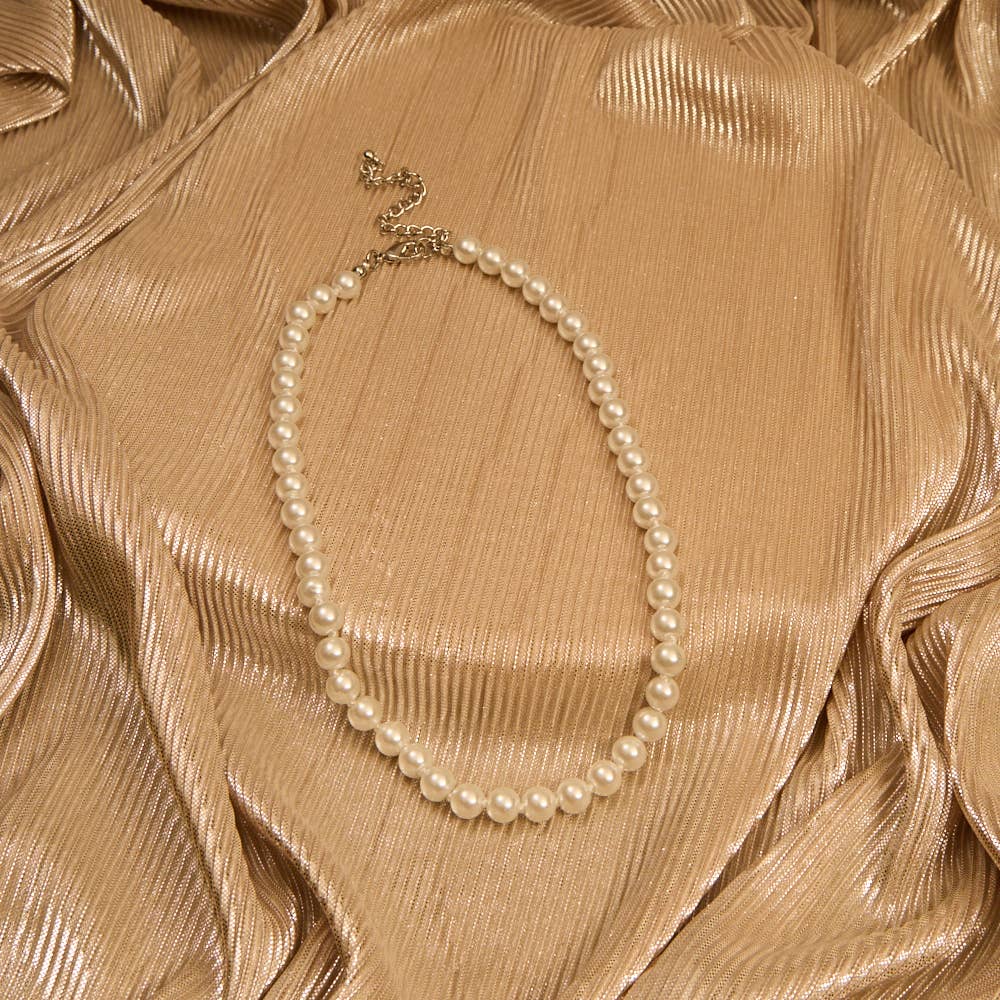 Pearl necklace on a textured beige fabric background