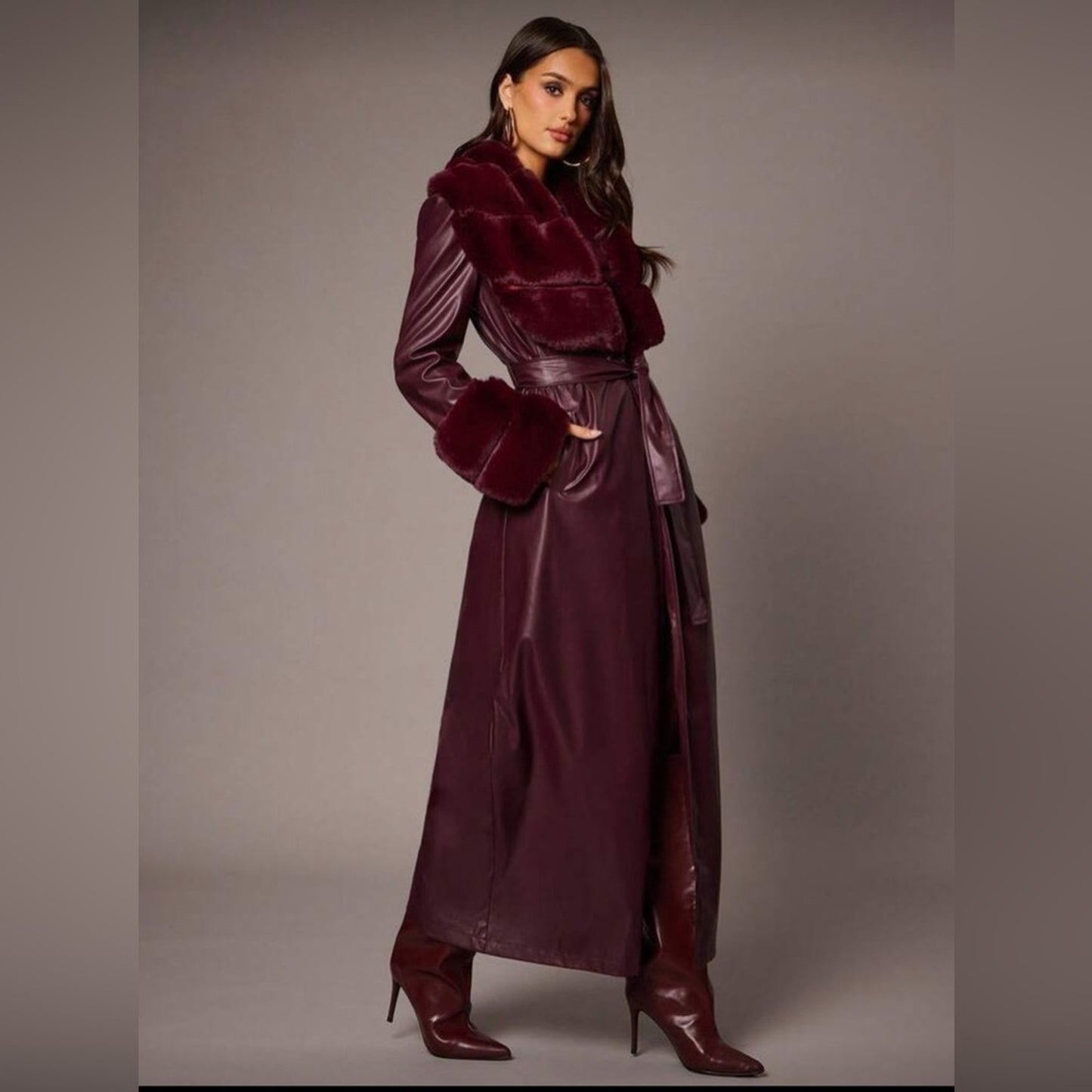 Woman wearing a burgundy outfit with a matching coat and skirt on a plain background