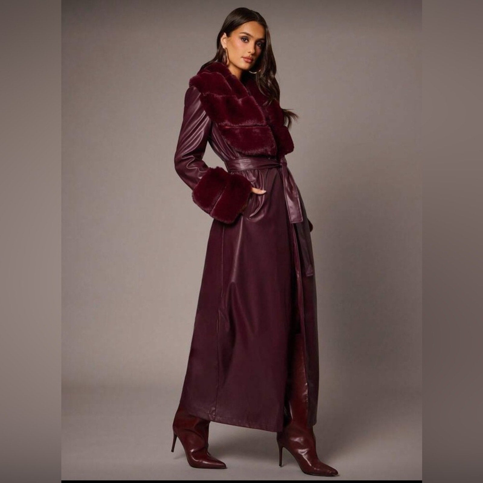 Woman wearing a burgundy outfit with a matching coat and skirt on a plain background