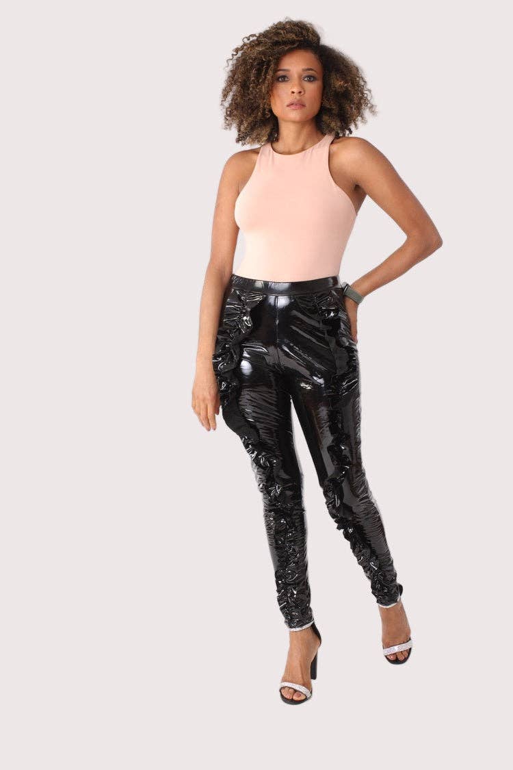 Woman wearing black sequin pants and a pink top on a white background