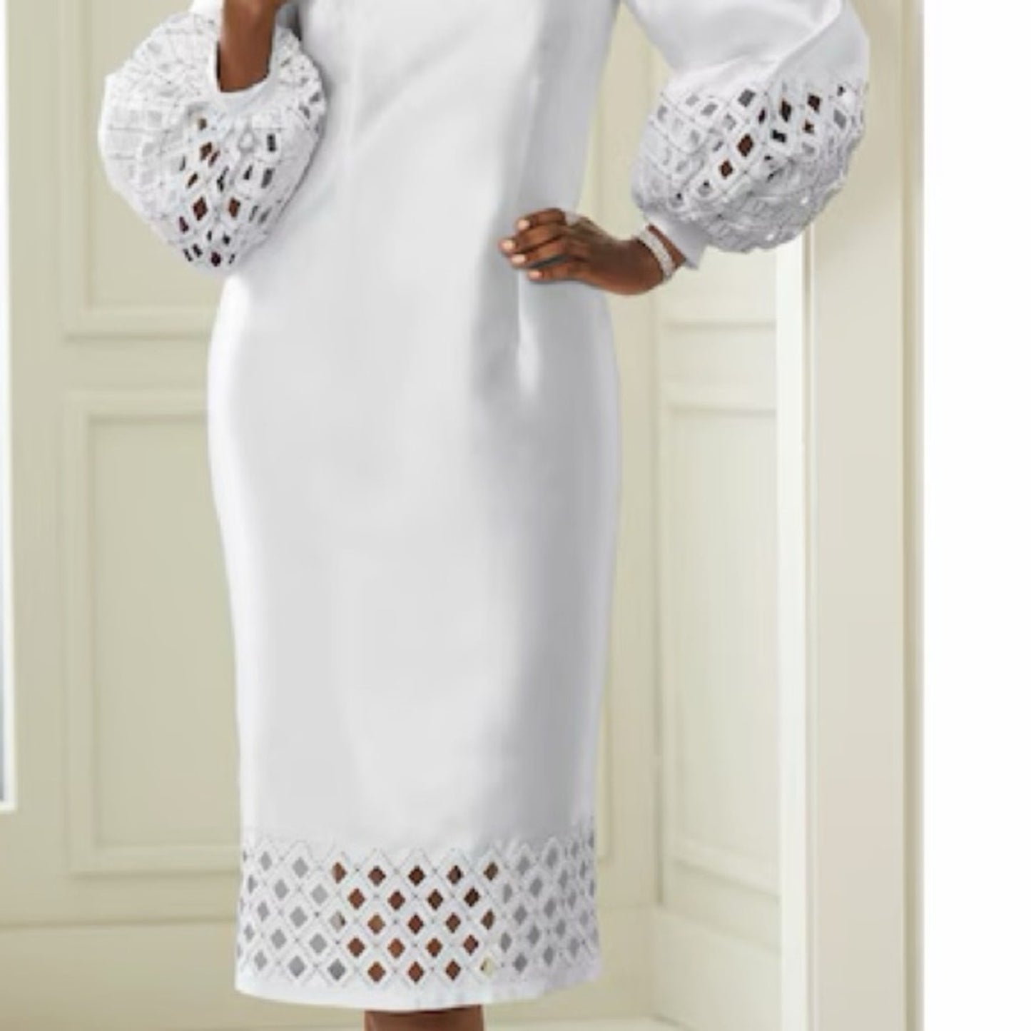 White dress with lace details on sleeves and hem against a neutral background