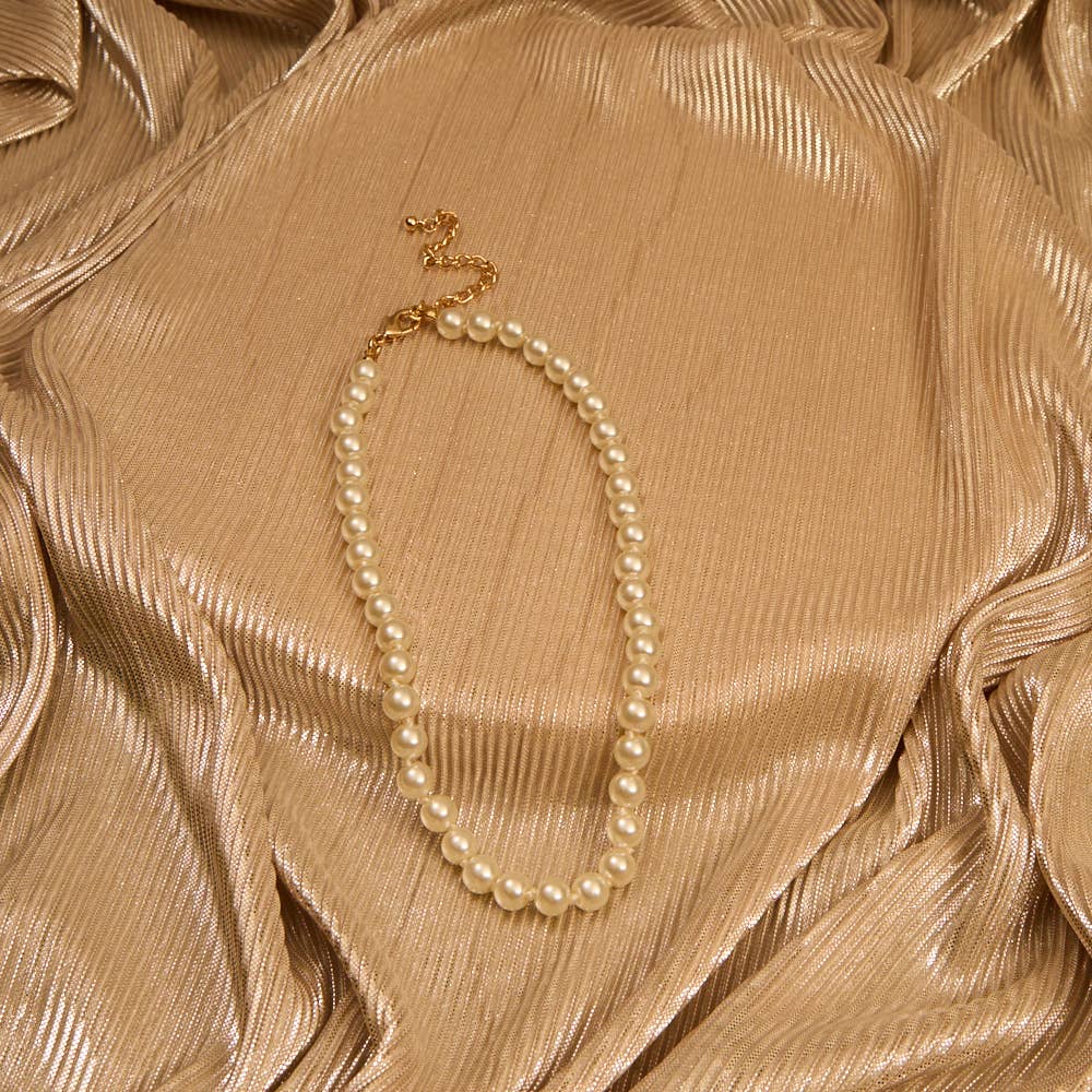 Pearl necklace on a textured beige fabric background