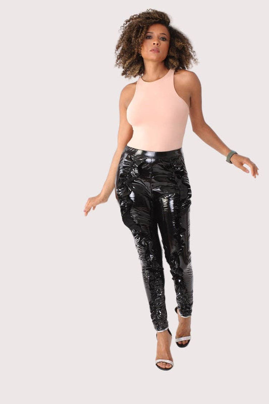 Woman wearing black sequin pants and a pink top on a white background