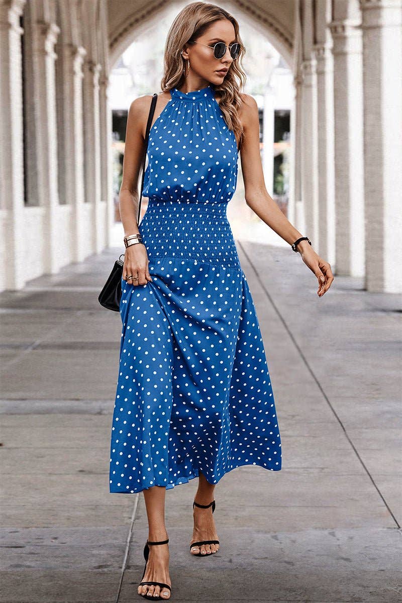 Woman wearing a blue polka dot dress walking outdoors.
