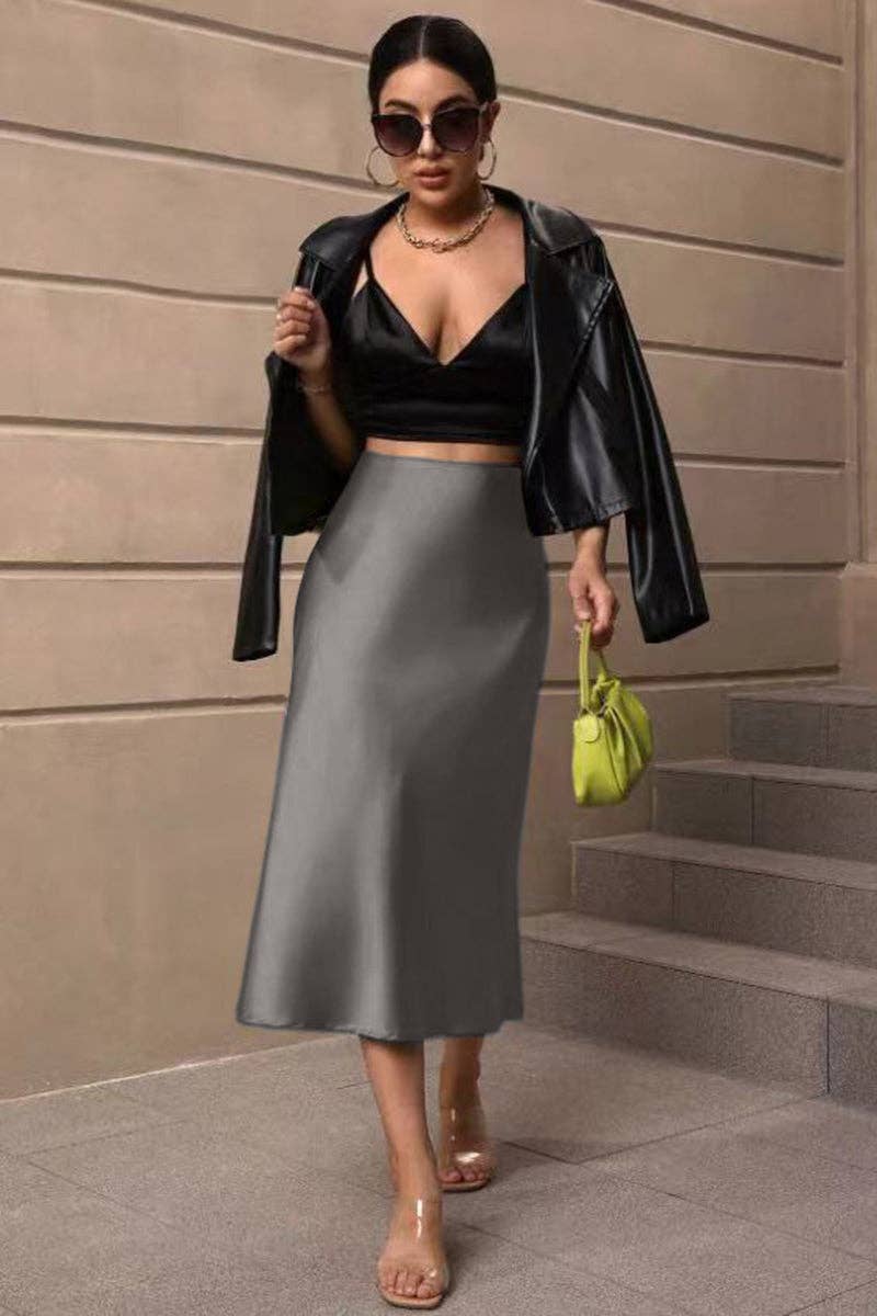 Woman in black leather jacket, black top, gray skirt, and sunglasses standing on steps.