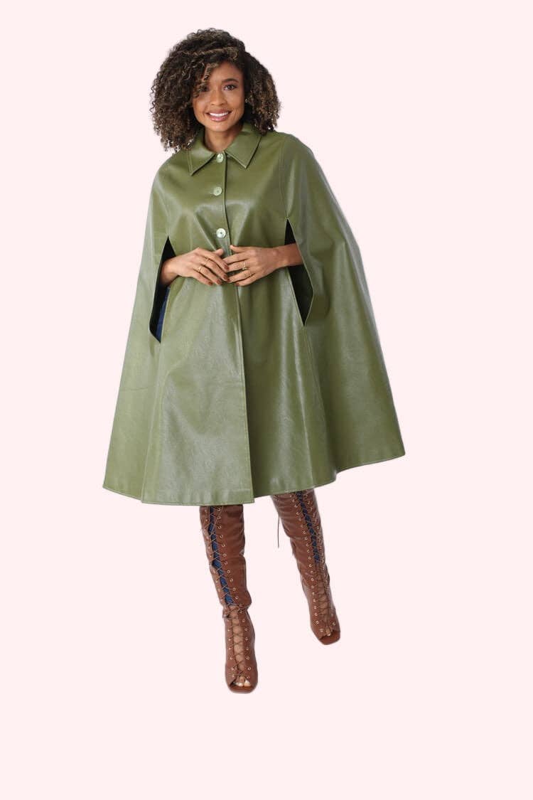 Woman wearing a green cape over a dress with brown boots on a white background