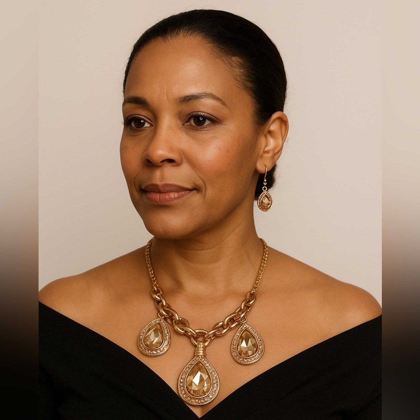 Woman wearing a gold necklace and earrings against a neutral background