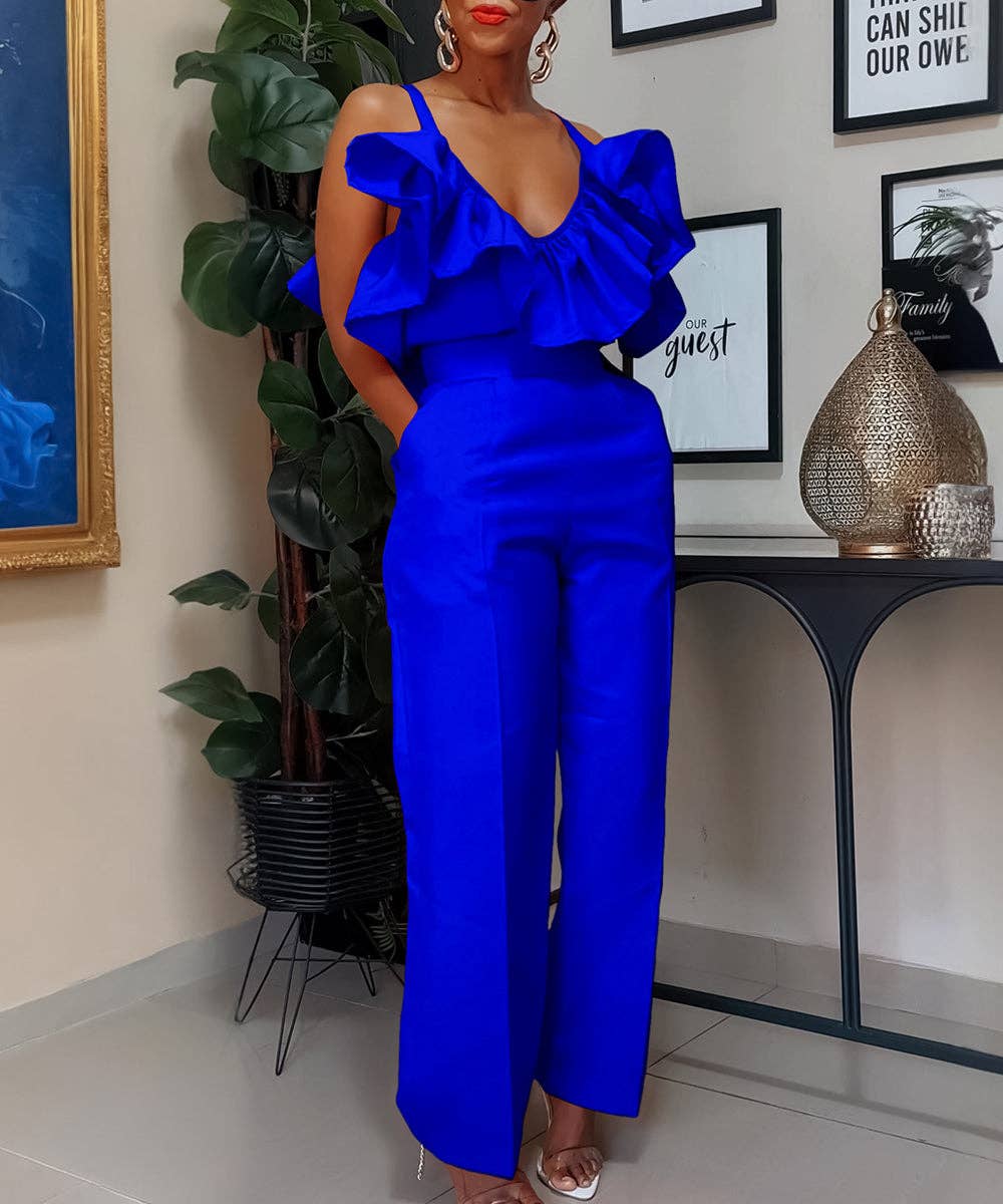 Woman wearing a blue ruffled jumpsuit in an indoor setting with decor elements.