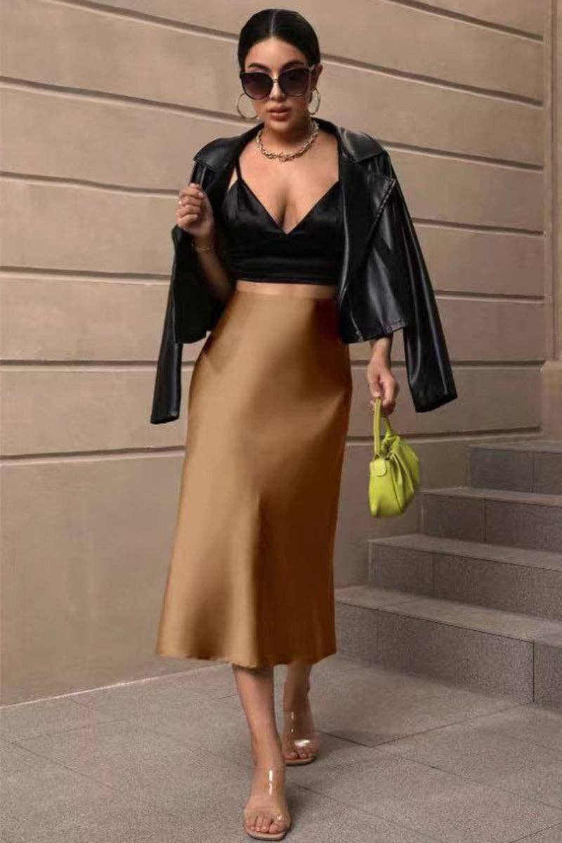Woman in black leather jacket, black top, and gold skirt standing on steps.