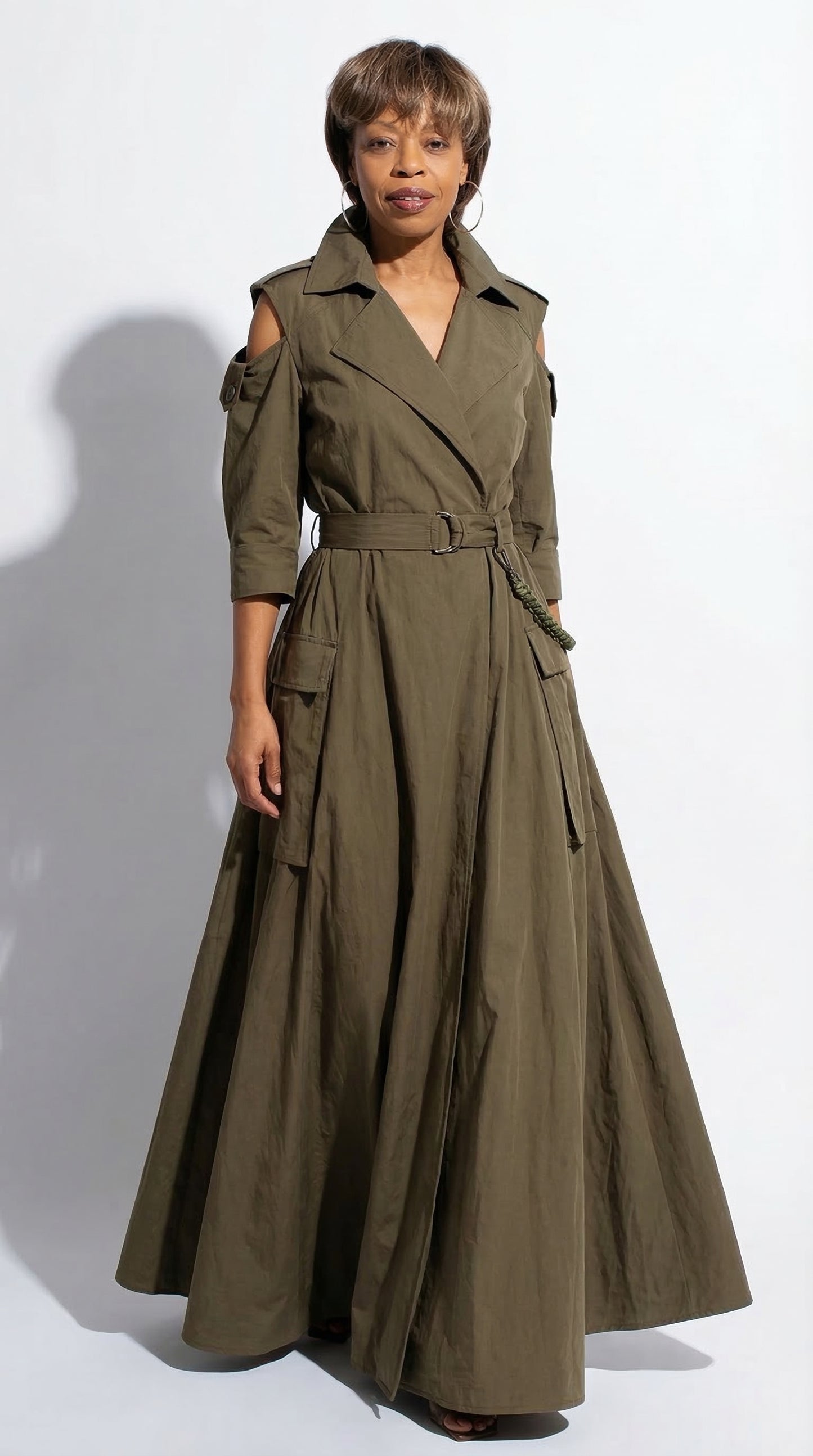 Woman wearing a long olive green trench coat on a white background