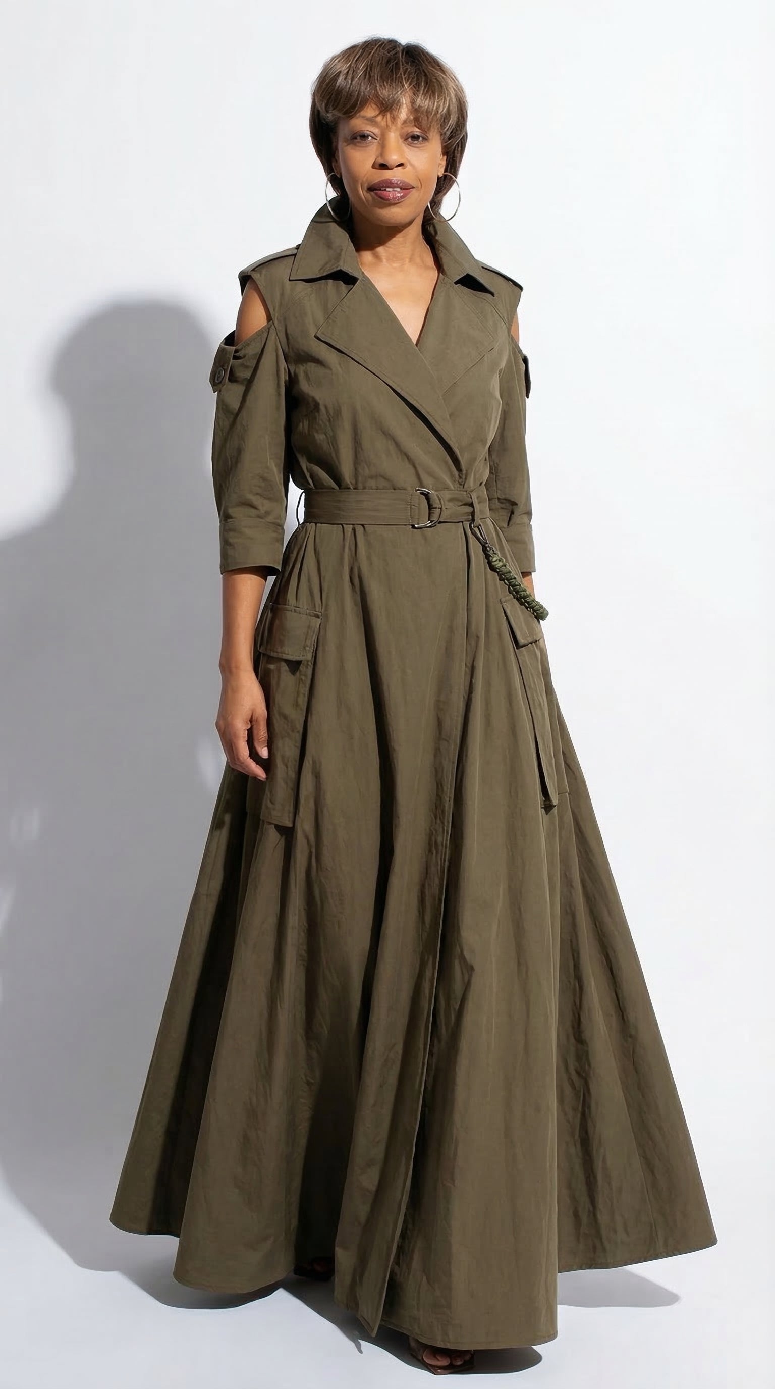 Woman wearing a long olive green trench coat on a white background