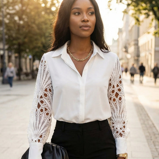 Woman wearing a white blouse with lace sleeves and black pants on a city street.