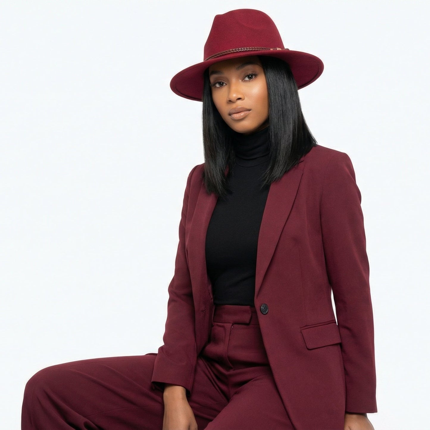 Woman wearing a maroon suit and hat on a white background