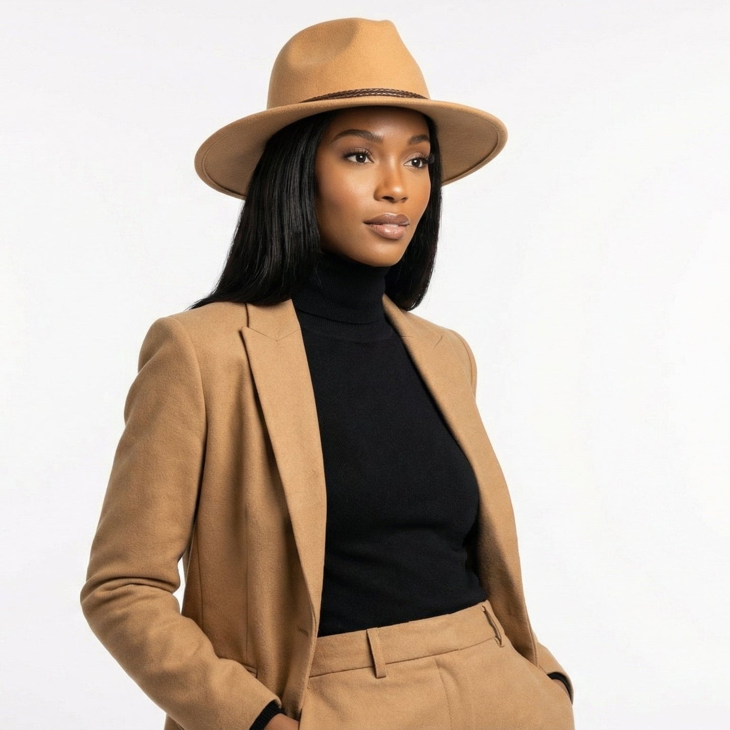 Woman wearing a beige hat, blazer, and pants on a white background