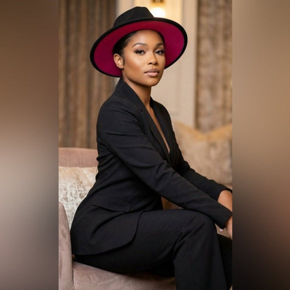Woman wearing a black suit and red hat sitting on a couch.