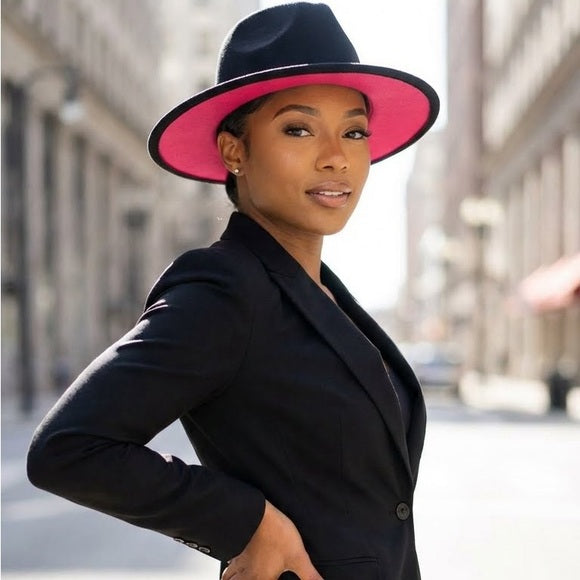 Woman wearing a black coat and pink-rimmed hat on a city street.