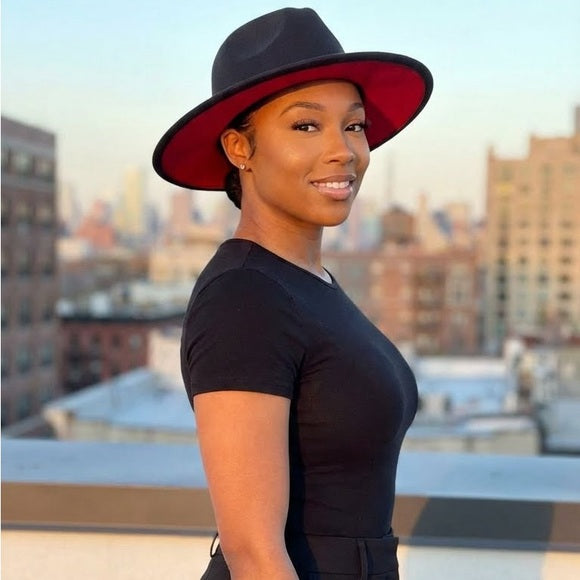 Woman wearing a black dress and red hat with a cityscape background