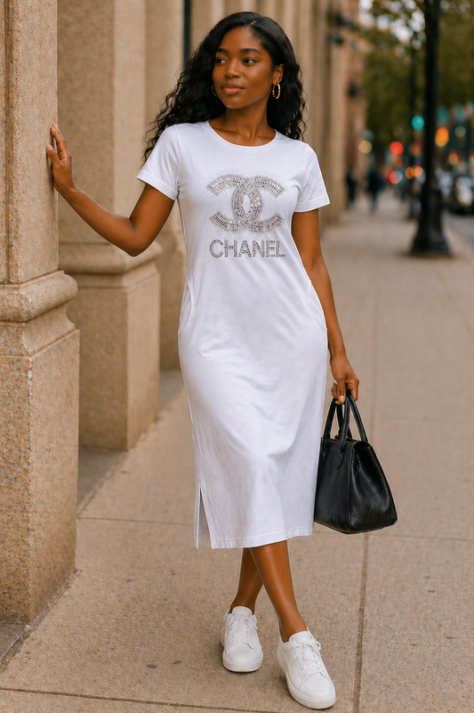Woman wearing a white t-shirt with Chanel logo and text, standing on a sidewalk.