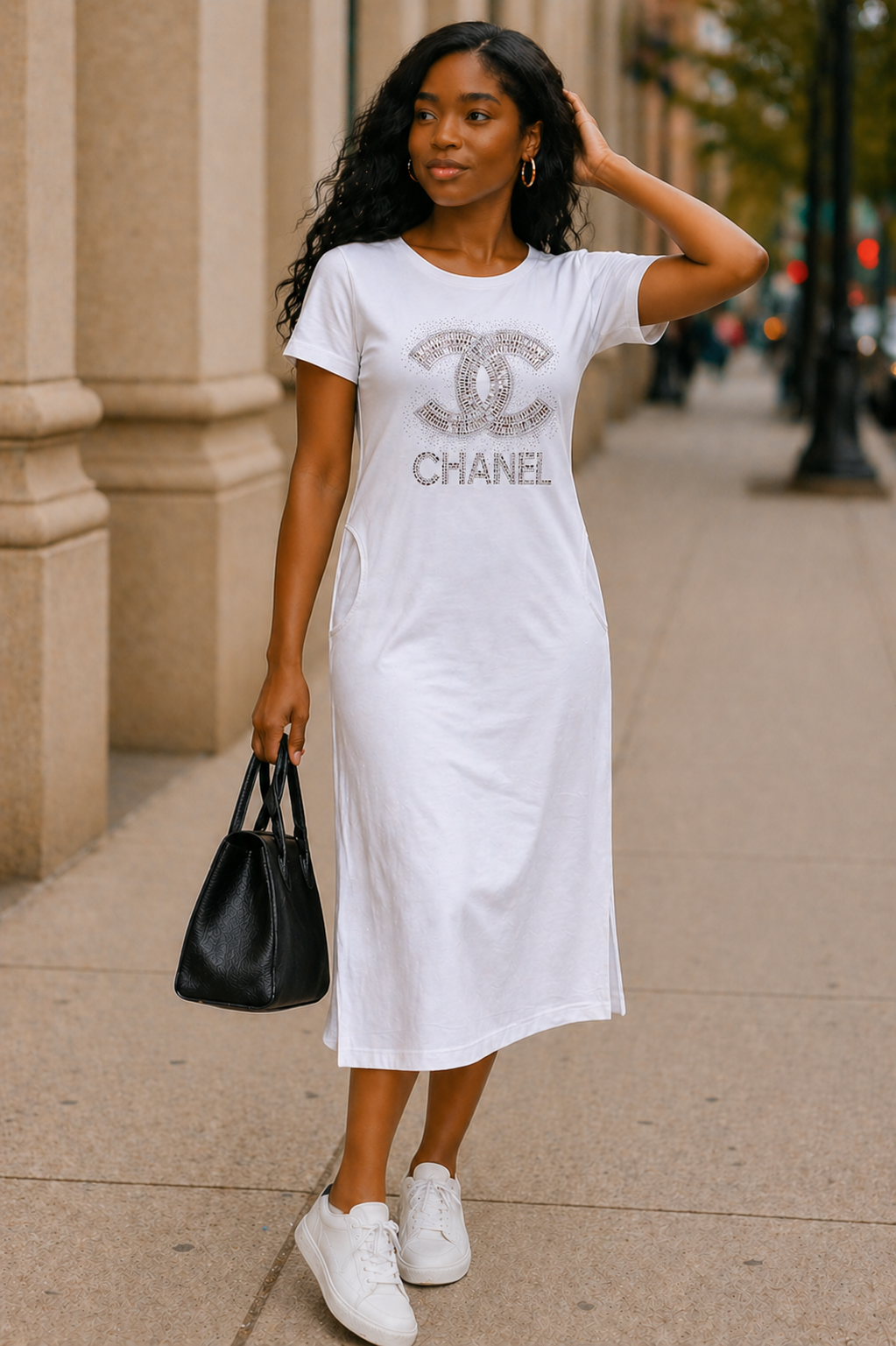 Woman wearing a white dress with a Chanel logo on a city street.