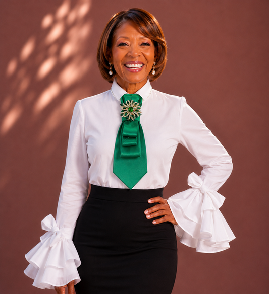 Woman wearing a white blouse with ruffled sleeves and a green tie against a brown background