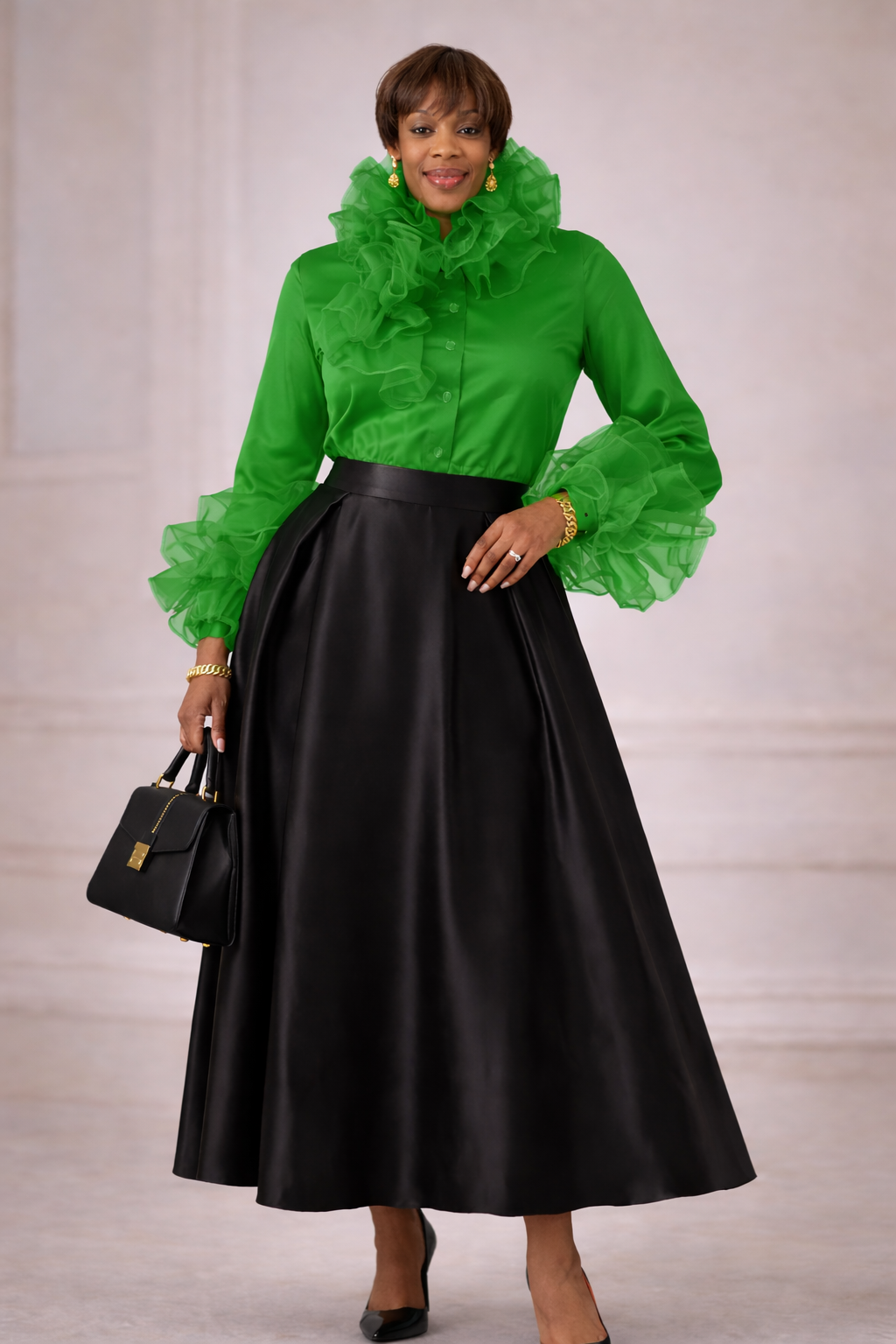 Woman wearing a green blouse with ruffled details and a black skirt, holding a black handbag.
