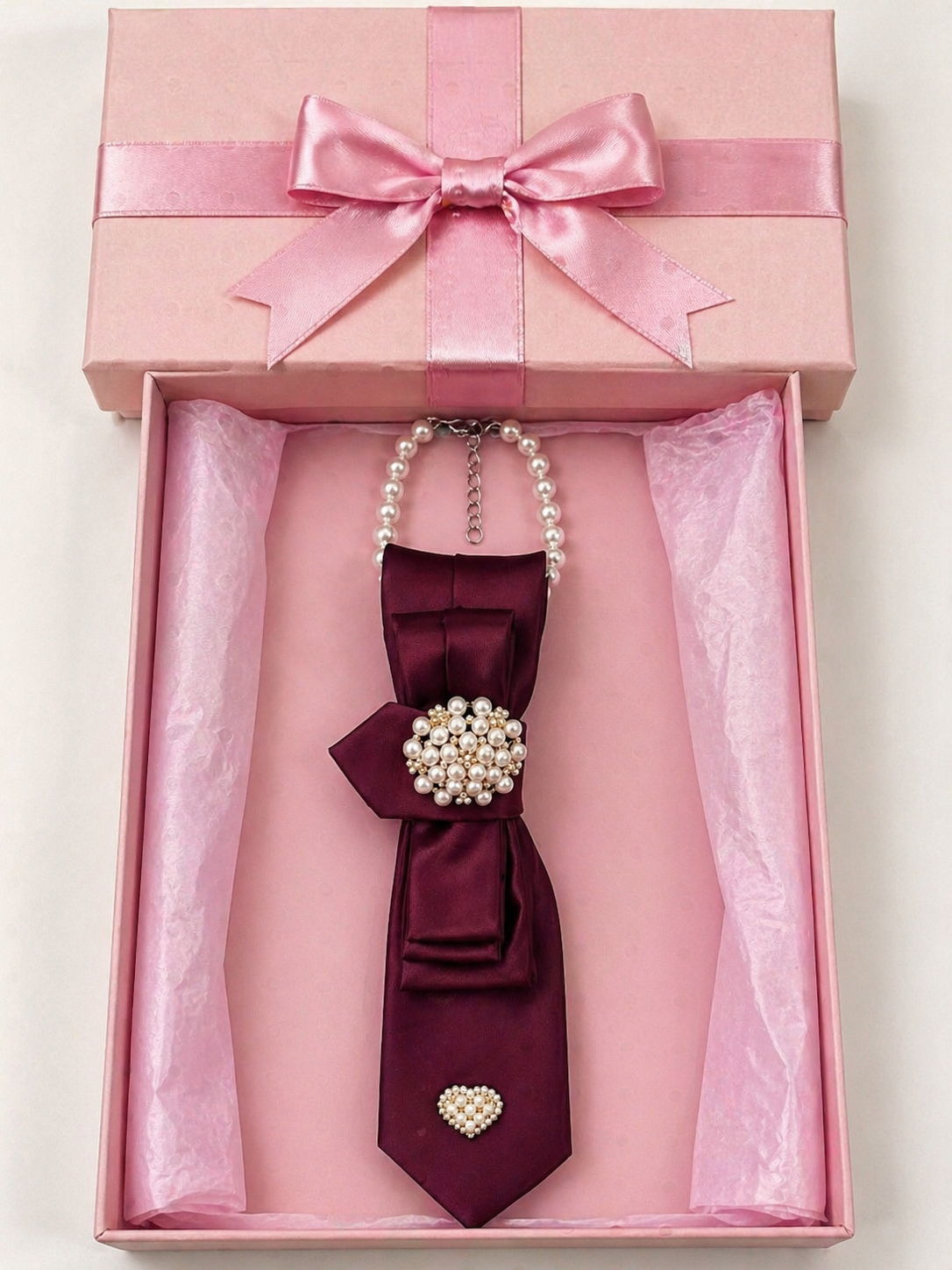 Maroon bow tie with pearl embellishments in a pink gift box.