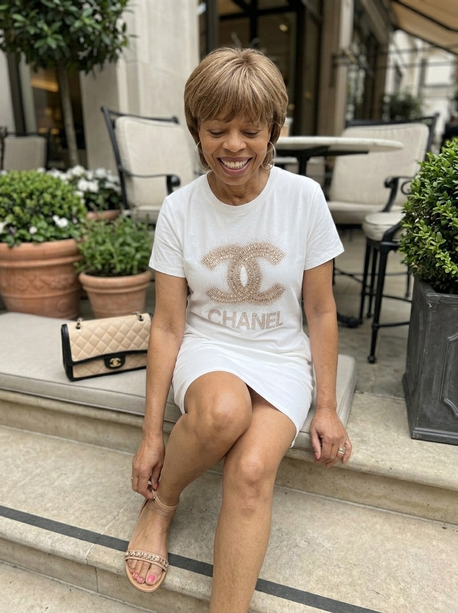 Woman sitting on steps wearing a Chanel logo t-shirt with a blurred background