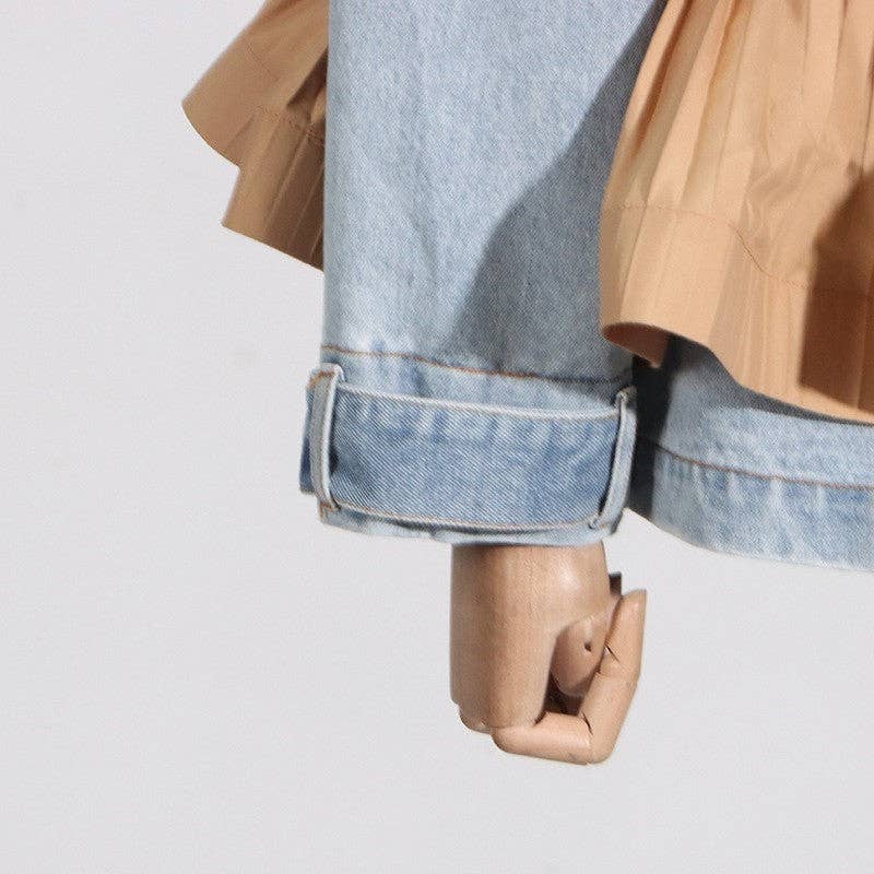Close-up of a person wearing rolled-up jeans with a beige jacket on a light gray background
