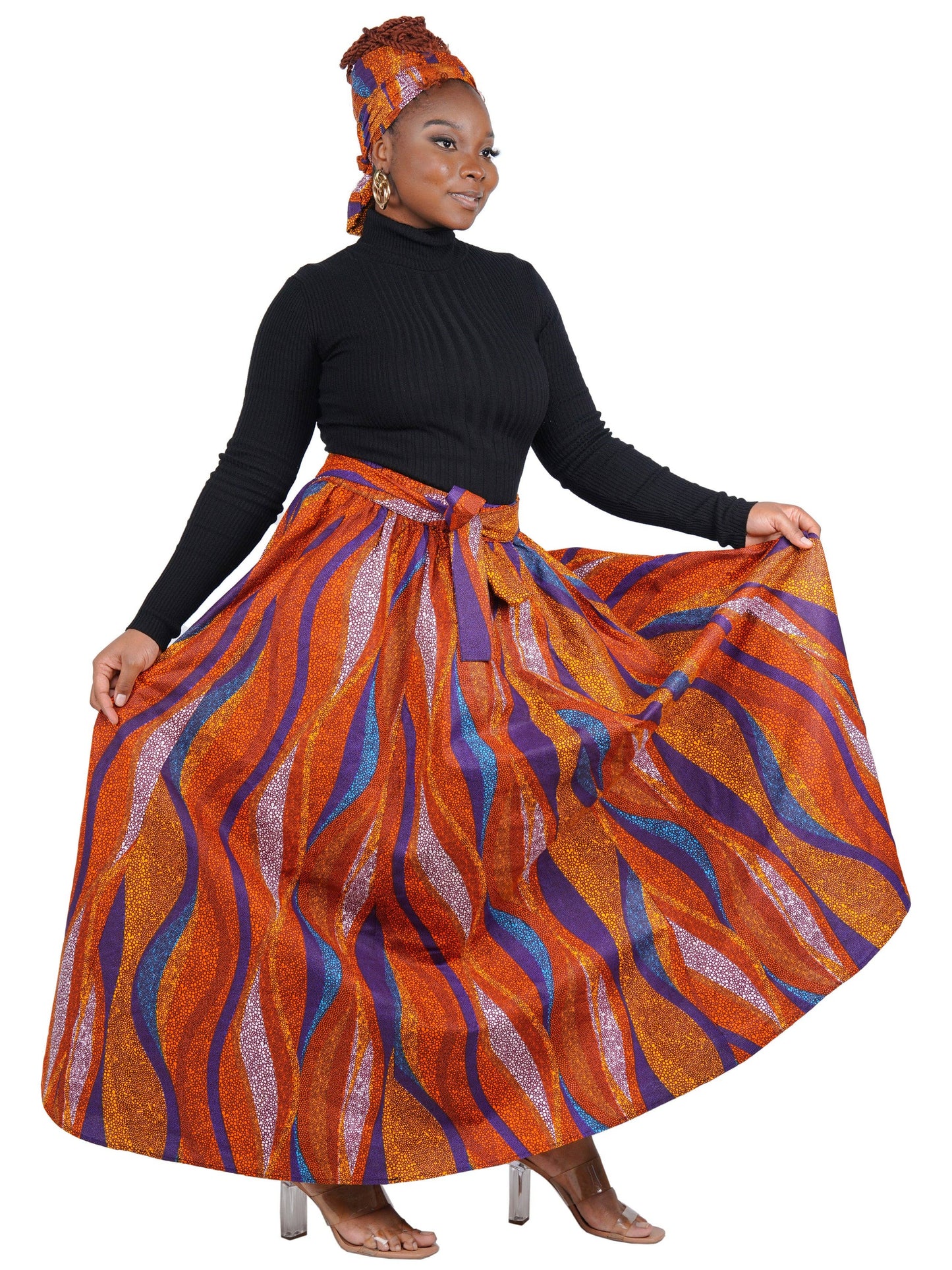 Woman wearing a black top and orange patterned skirt on a white background