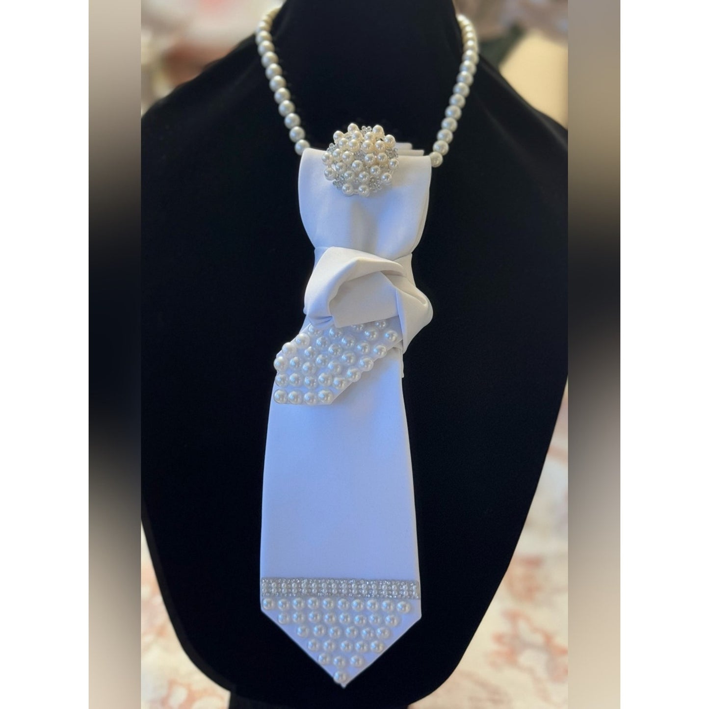 Decorative tie with pearls on a black stand