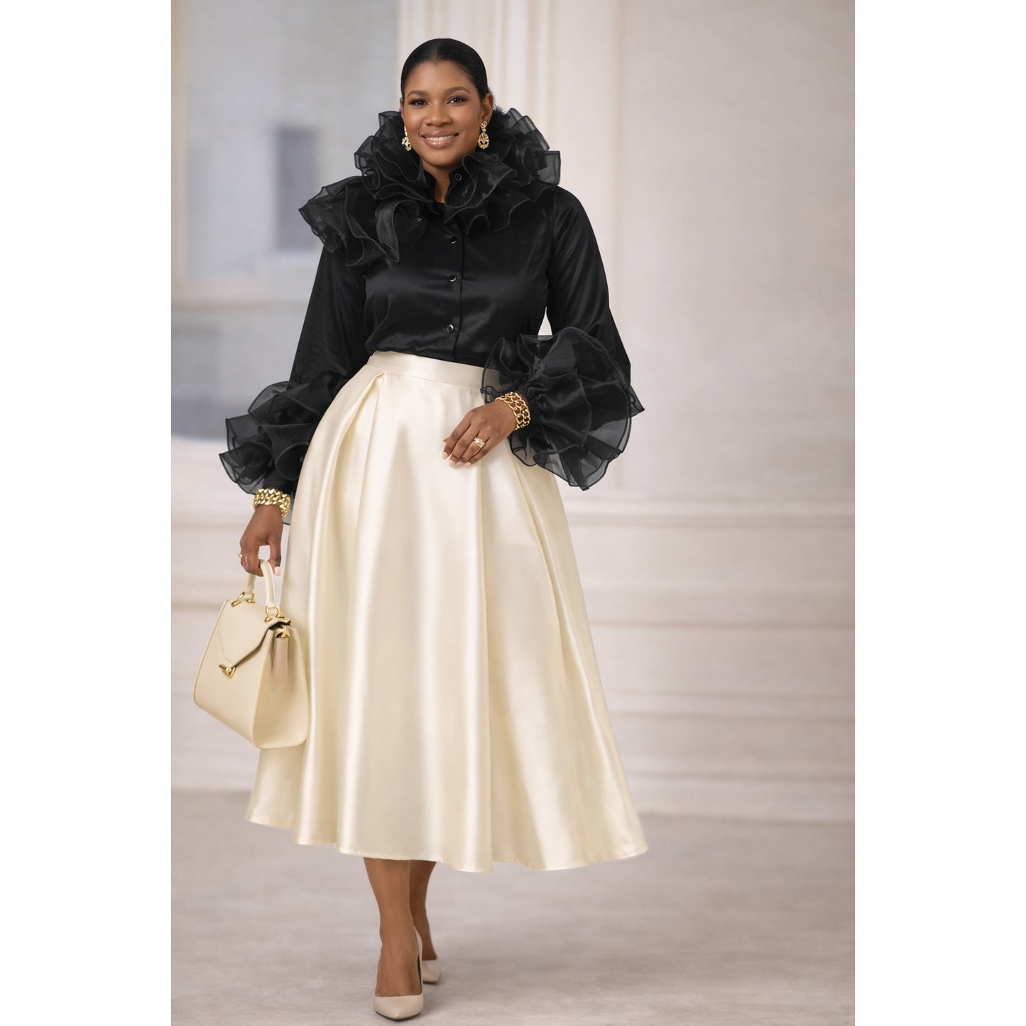 Woman wearing a black top with ruffled sleeves and a cream skirt, holding a beige handbag.