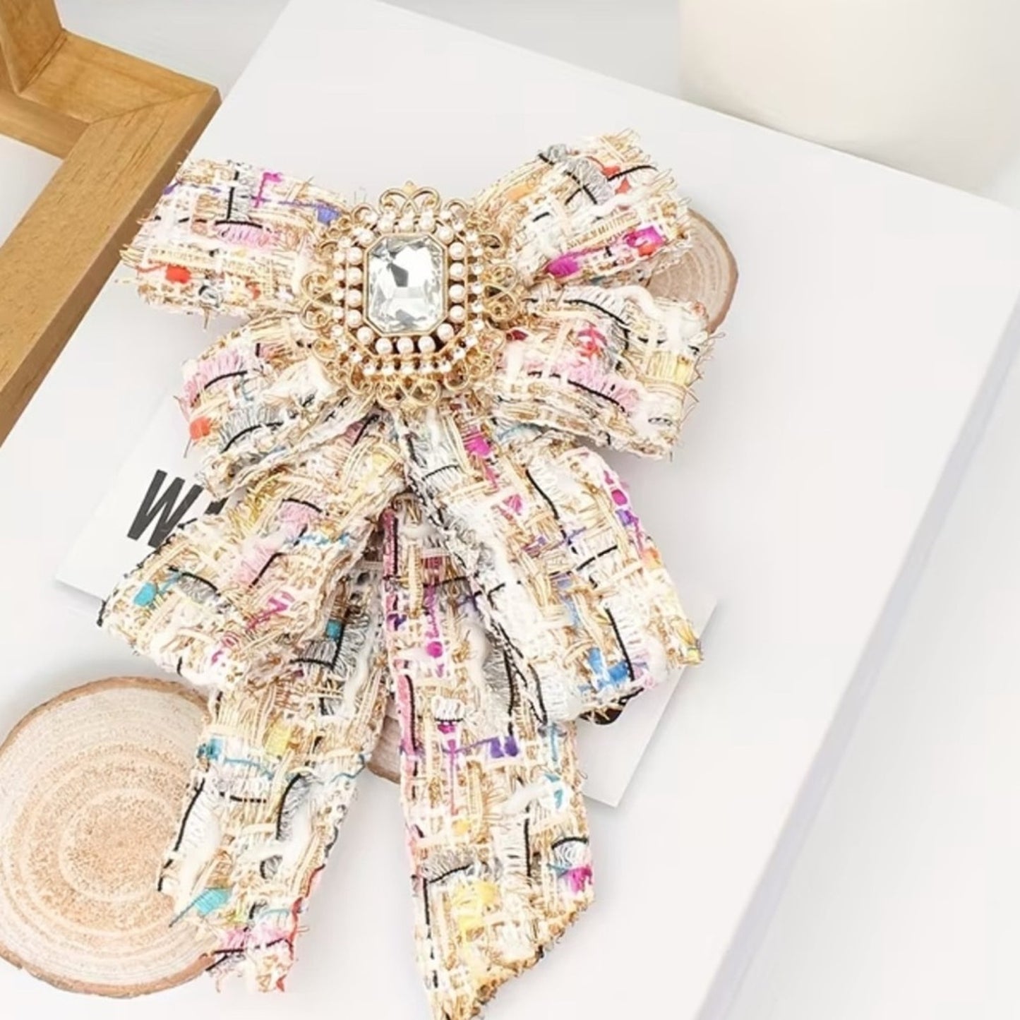 Decorative bow with colorful pattern and gemstone on a white surface