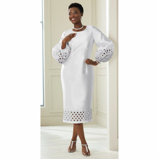 Woman wearing a white dress with intricate cut-out sleeves in a minimalistic setting.