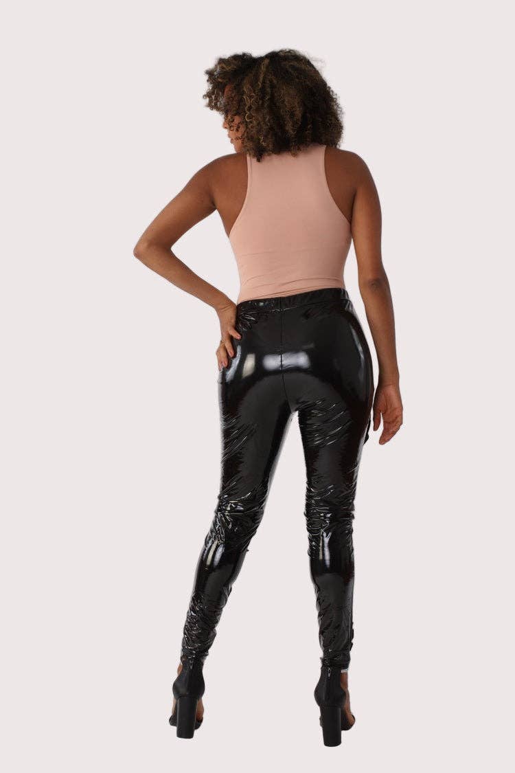 Person wearing black shiny pants and a beige top on a white background