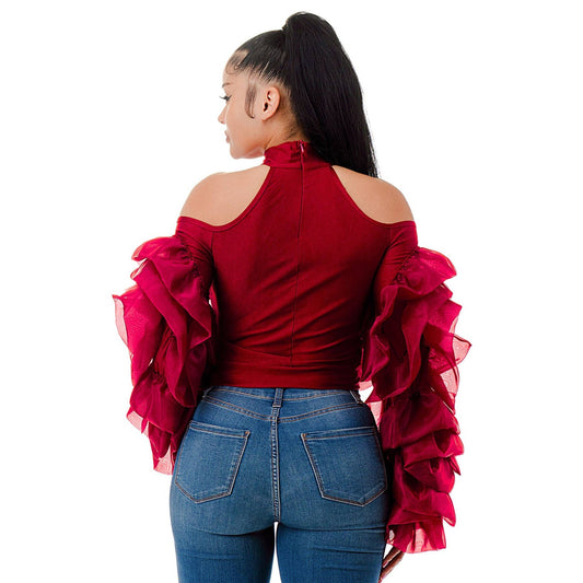 Person wearing a red off-shoulder top with ruffled sleeves and blue jeans on a white background