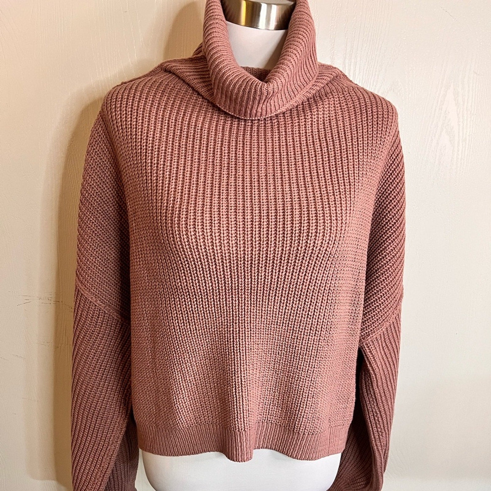 Pink knitted sweater on a mannequin against a plain background