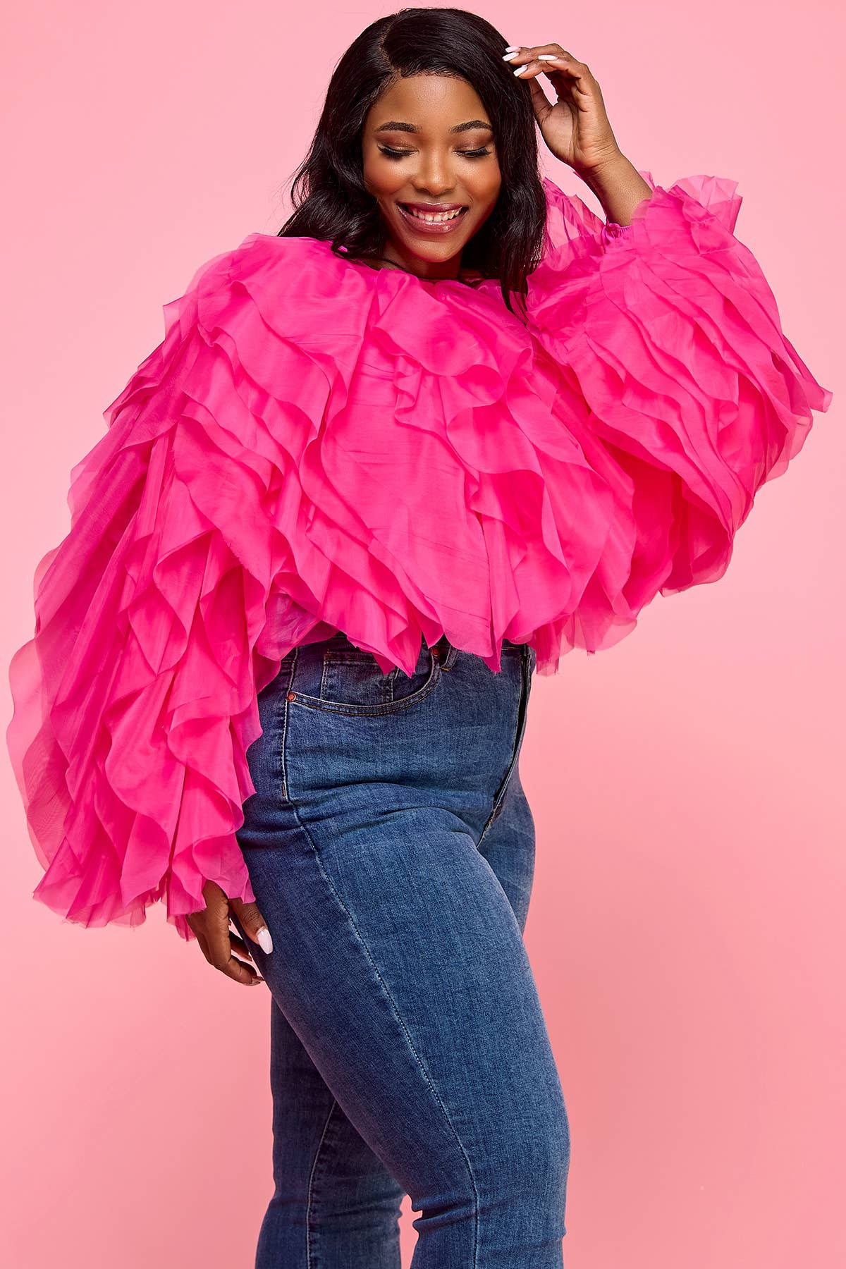 Woman wearing a bright pink ruffled top against a pink background