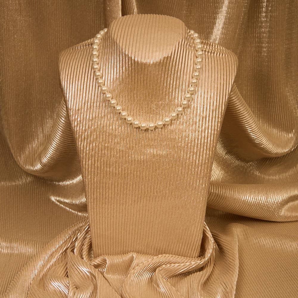 Mannequin wearing a beige dress with a pearl necklace against a textured beige background