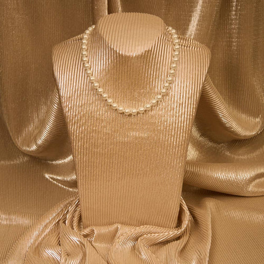 Mannequin wearing a beige dress with a pearl necklace against a textured beige background
