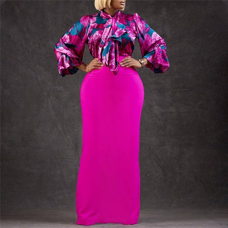 Woman wearing a colorful top and bright pink skirt against a dark background