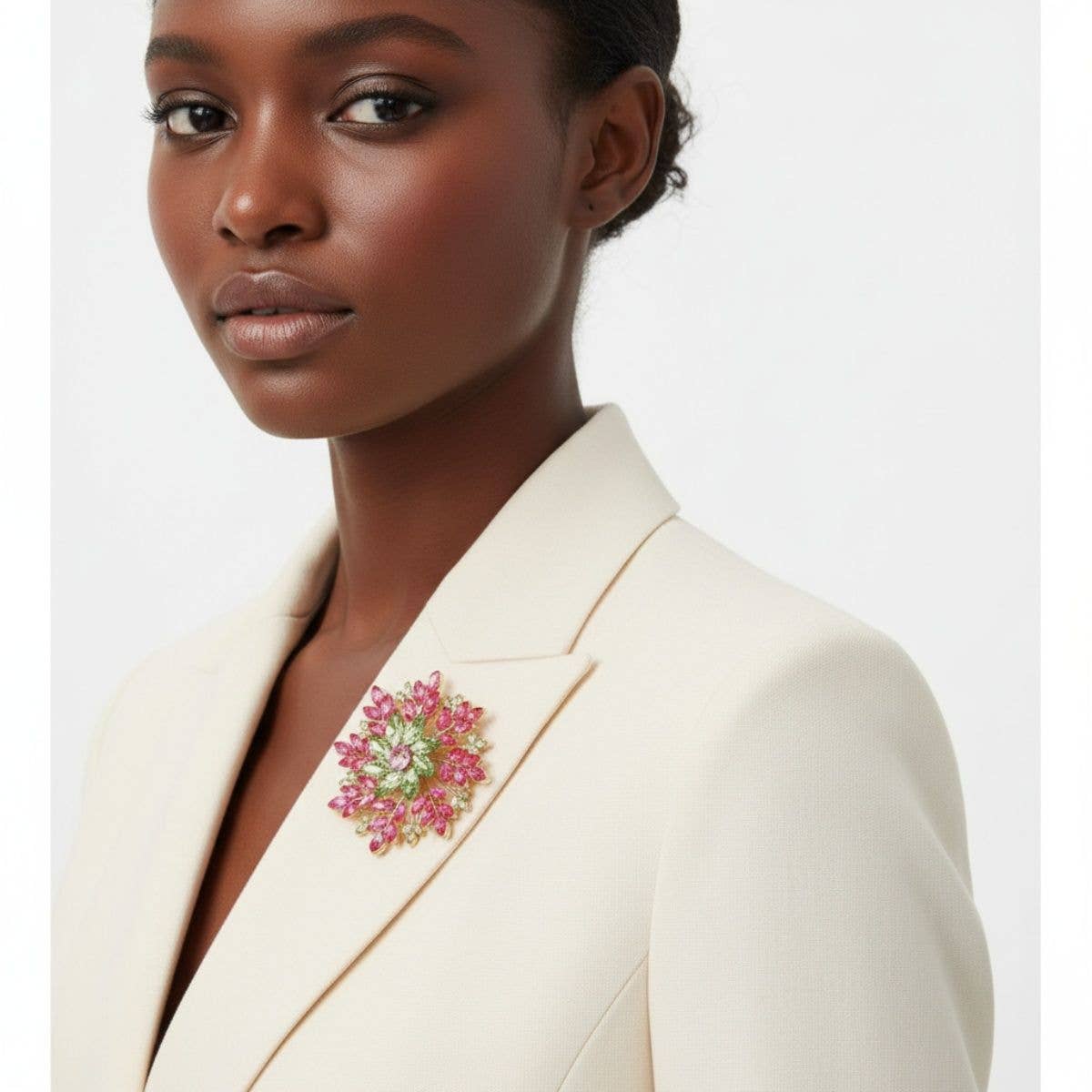 Woman wearing a cream blazer with a floral brooch on a white background