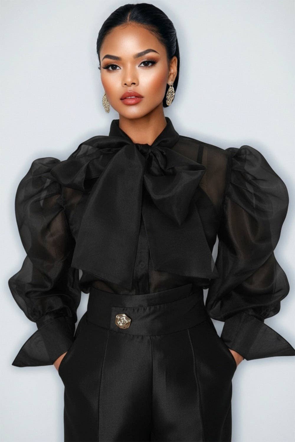 Woman wearing a black blouse with puffed sleeves and a high collar against a white background